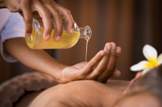 massaggio sarvanga abhyanga con olio sulla schiena di una persona prona